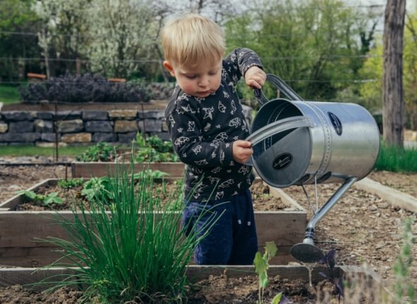 Young student learning agricultural science by watering plants